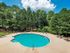 round swimming pool with large sundeck surrounded by trees