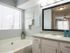 Bathroom with white shaker style cabinets, garden tub and framed mirror