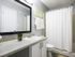 Bathroom with white shaker style cabinets, garden tub and framed mirror