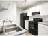 White shaker style kitchen cabinet with stainless pulls and subway tile backsplash with black appliances