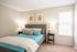 Furnished model bedroom with plush carpeting and bright light from window