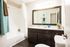 Renovated bathroom with dark wood cabinets, framed mirror, upgraded designer lighting and wood inspired plank flooring