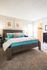 Furnished model bedroom with plush carpeting and bright light from window and view into walk-in closet