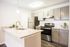 Beautiful renovated kitchen with neutral shaker cabinets and upgraded pulls, granite countertops, designer lighting package and stainless steel appliances