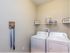San Mateo Apartments Kissimmee Florida laundry room with full size washer and dryer and storage rack above appliances