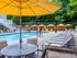 The Henry Apartments, exterior, sparkling blue pool, gray lounge chairs, yellow umbrella at gray table, trees