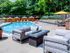 The Henry Apartments, exterior, sparkling blue pool, gray lounge chairs, yellow umbrella at gray table, trees, shaded tent seating, gray couches, gas fire pit