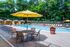 The Henry Apartments, exterior, sparkling blue pool, gray lounge chairs, yellow umbrella at gray table, trees, shaded tent seating