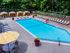 The Henry Apartments, exterior, sparkling blue pool, gray lounge chairs, yellow umbrella at gray table, trees, shaded tent seating
