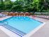 The Henry Apartments, exterior, sparkling blue pool, gray lounge chairs, yellow umbrella at gray table, trees, shaded tent seating