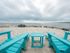 Private beach with two blue wooden chairs and table