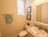 Bathroom with framed mirror, sink with cabinets, toilet, and small window