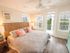Bedroom with king size bed, two bedside tables, ceiling fan, and windows with balcony door