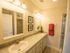 Bathroom with dual sinks with cabinets, two framed mirrors, and a walk-in shower