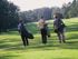 Three figures jaunt through the Celebration Golf Course with their clubs |  Trees boarder the course |  Mirasol at Celebration