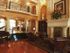 Leather chairs for lounging surround an ottoman |  Piano | Small library with seating | Balcony overlooking | Mosaic at Celebration