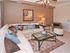 One bedroom model living room | Large sofa with coffee table |  Lounge chair with ottoman and side table | Small chandelier | Mosaic at Celebration