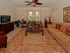 Two bed two bath model living room | Several sofas, chairs, and tables | Entertainment center | Large windows | Ceiling fan | Mosaic at Celebration