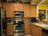 Mirasol at Celebration, interior, kitchen, brown cabinets, stainless steel appliances, refrigerator, stove/ovven, microwave, dishwasher, pass-through window to other room,