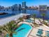 Apartments Downtown Jacksonville FL - The Strand - Resort-Style Pool with Sun Lounge Chairs, Palm Trees, and City View