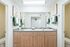Modern bathroom with dual sinks, stylish wood cabinetry, and elegant decor.