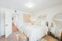 Bright and inviting bedroom featuring a comfortable bed, stylish decor, and a large mirror enhancing space.