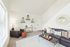 Bright and inviting living room with modern decor, featuring a leather sofa, stylish shelving, and a large window.