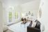 Sunlit modern living room with large windows, minimalist decor, and a cozy seating area.
