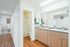 Bright and modern bathroom with wooden cabinetry, double sinks, and a glass-enclosed shower.