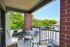 Cozy apartment balcony with seating, offering a view of lush green trees and a vibrant neighborhood.