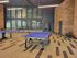 Inviting recreational space with modern table tennis setup, stylish wood flooring, brick accents, and generous windows.