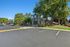 Inviting apartment complex with lush green landscaping and spacious parking area under a clear blue sky.