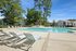 Inviting apartment community pool area surrounded by lush greenery and modern lounge chairs, perfect for relaxation.
