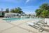 Luxurious apartment complex showcasing a pristine swimming pool and modern poolside loungers against a backdrop of charming architecture and lush greenery.