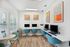 Contemporary workspace with vibrant blue chairs, sleek computers, and modern art, perfect for productivity and creativity.