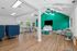 Vibrant community lounge featuring modern seating, green accent wall, and ample natural light.