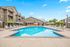 Inviting apartment complex with a sparkling pool surrounded by lounge chairs and umbrellas, perfect for relaxation and leisure.