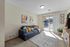 Bright and cozy living room featuring a modern sofa, vibrant decor, and large sliding glass doors leading to a sunlit patio.