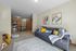 Modern living room with stylish decor, cozy couch, vibrant cushions, and an open-plan kitchen in the background.
