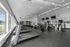 Modern fitness center with state-of-the-art treadmills, stationary bikes, and strength equipment, featuring bright natural lighting from large windows.
