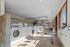 Spacious and well-lit laundry facility with modern washing machines and dryers, featuring tiled floors and large windows for natural light.