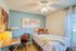 Cozy bedroom with elegant decor featuring a comfortable bed, stylish desk, and vibrant pillows, illuminated by soft natural light.