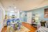 Bright and inviting open-plan dining and living area featuring a modern kitchen with stainless steel appliances, colorful decor, and comfortable seating.