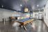 Contemporary recreation room featuring a sleek pool table, lounge seating, and dynamic overhead lighting, perfect for social gatherings.