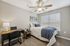 Cozy bedroom with elegant decor, featuring a comfortable bed, workstation with lamp, large windows, and stylish ceiling fan.