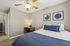 Inviting bedroom with modern decor, featuring a cozy bed with blue accents and a stylish work desk under soft ambient lighting.