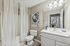 Modern bathroom featuring elegant lighting, minimalist decor, and a sleek white vanity with a large mirror.