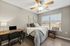 Cozy bedroom with modern decor, featuring a plush bed by a large window, sleek wooden floors, and a convenient workspace with a laptop.