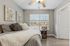 Inviting bedroom with warm decor, featuring elegant wall art, plush pillows, and a scenic view through large windows, creating a cozy and serene atmosphere.