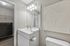 Elegant bathroom with modern fixtures, large mirror, and artistic wall decor, exuding a serene and sophisticated ambiance.